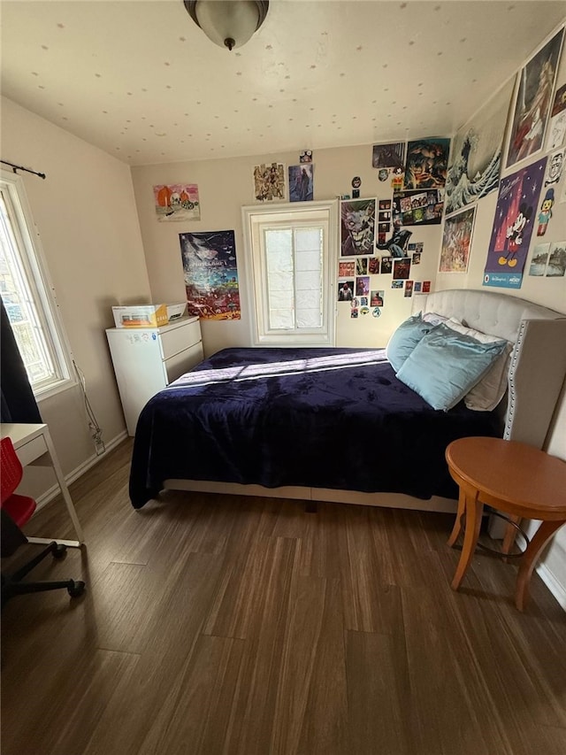 bedroom with multiple windows, baseboards, and wood finished floors