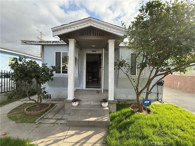 entrance to property featuring fence and stucco siding