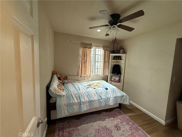 bedroom with ceiling fan, baseboards, and wood finished floors