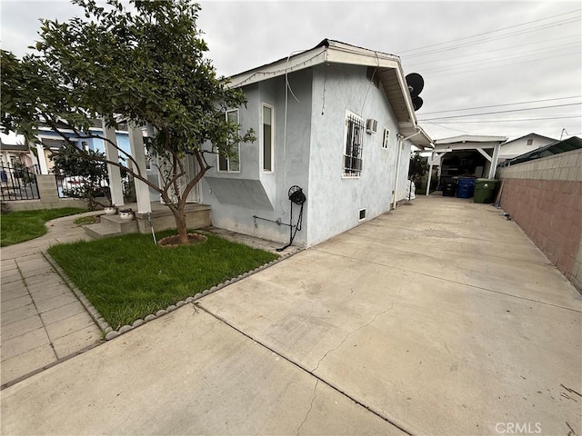 view of home's exterior with fence, driveway, and stucco siding