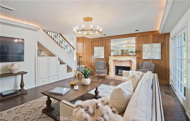 living area with a chandelier, stairs, visible vents, and wooden walls