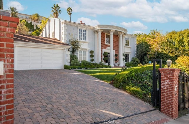 greek revival house with a garage, decorative driveway, brick siding, and stucco siding