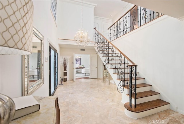 staircase featuring marble finish floor, a towering ceiling, and an inviting chandelier