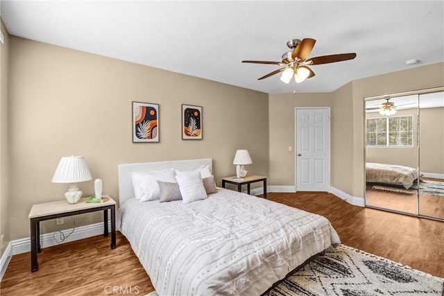 bedroom featuring ceiling fan, a closet, wood finished floors, and baseboards