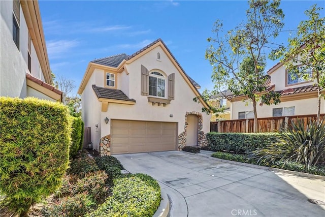 mediterranean / spanish home featuring a garage, fence, a tile roof, driveway, and stucco siding