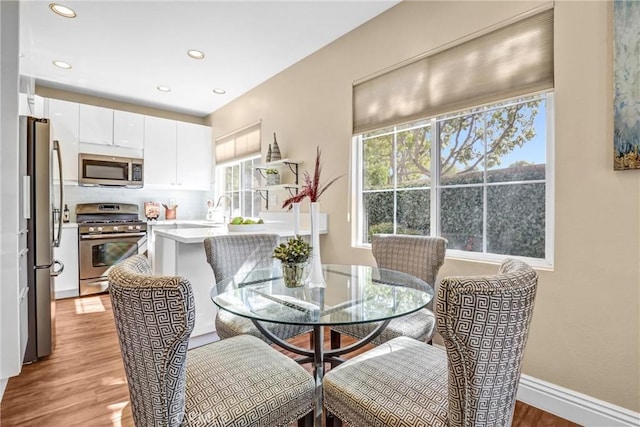 dining room featuring light wood-type flooring, baseboards, and recessed lighting