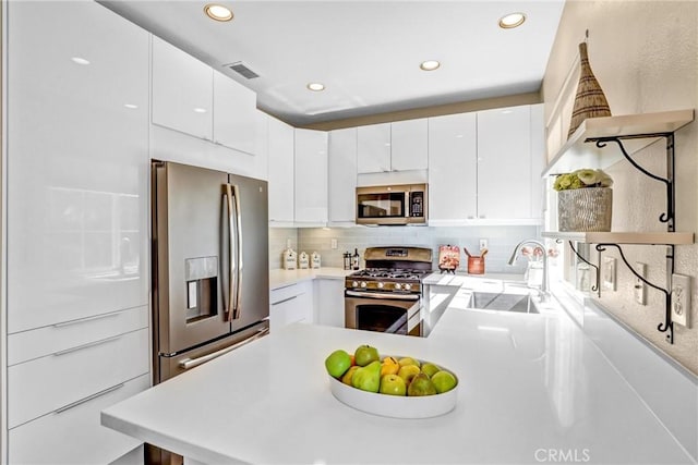 kitchen featuring visible vents, appliances with stainless steel finishes, a peninsula, light countertops, and a sink