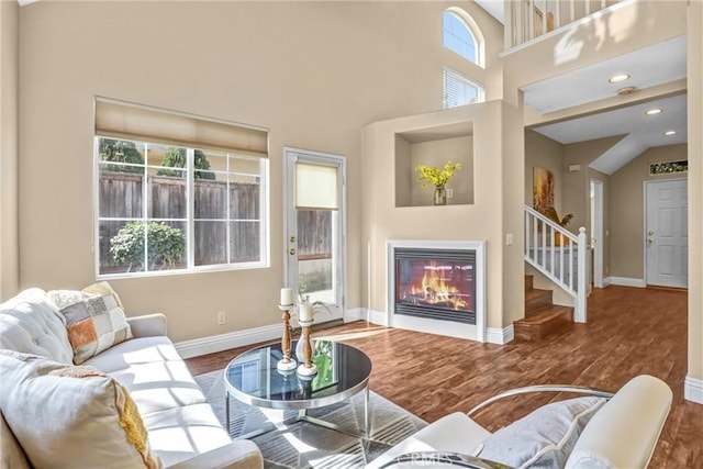 living area with a healthy amount of sunlight, baseboards, wood finished floors, and a glass covered fireplace