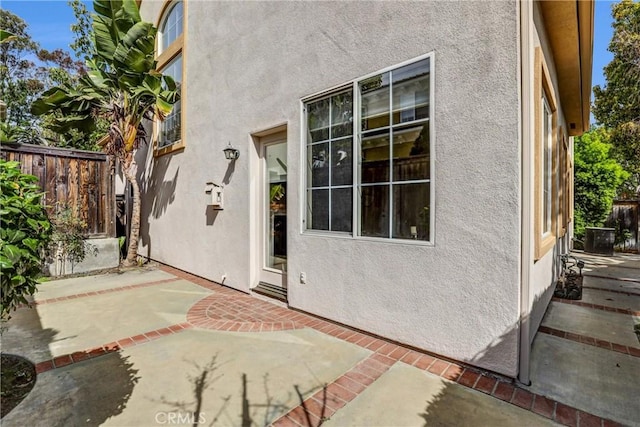 property entrance with a patio, fence, and stucco siding