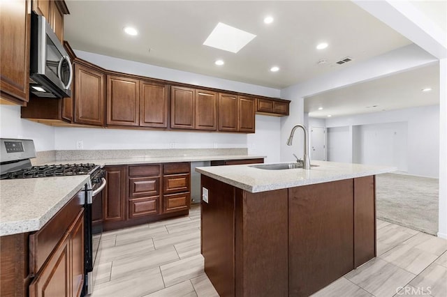 kitchen featuring stainless steel appliances, recessed lighting, light countertops, a sink, and an island with sink