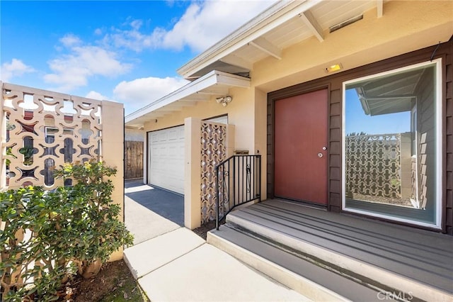 doorway to property featuring a garage and stucco siding