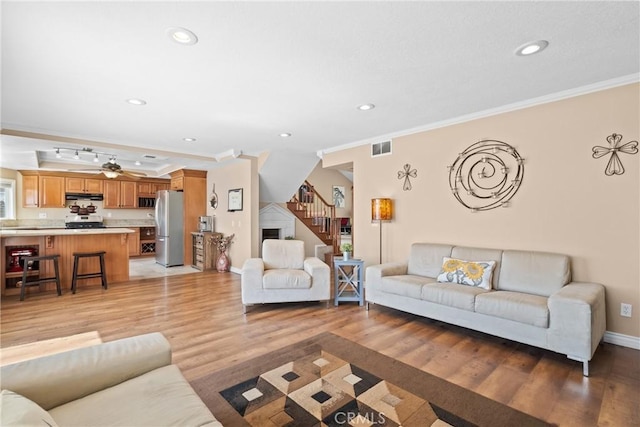 living area with light wood-type flooring, visible vents, recessed lighting, stairway, and crown molding