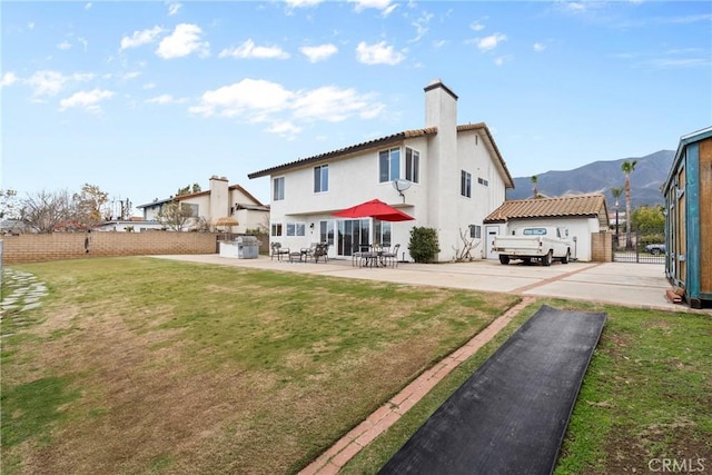 back of property featuring fence, a yard, stucco siding, a chimney, and a patio area