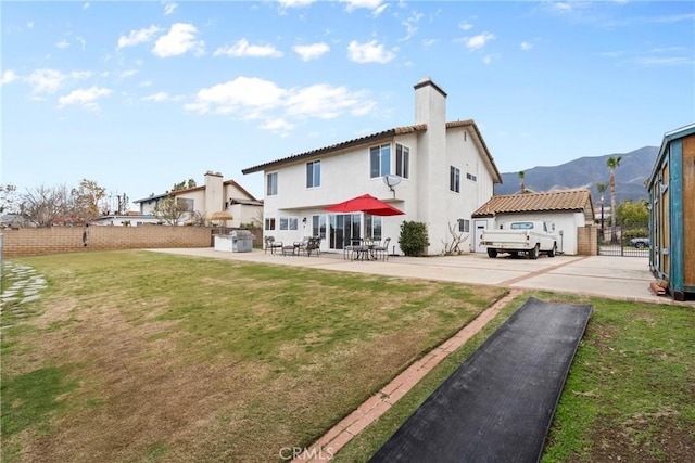 rear view of property featuring a yard, a chimney, stucco siding, and fence