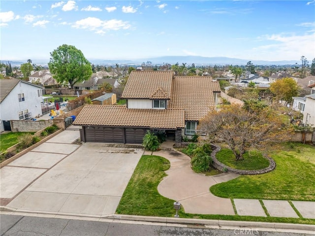 view of front of house featuring a front yard, concrete driveway, a garage, a tiled roof, and a residential view