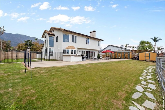 rear view of property featuring an outbuilding, a storage shed, fence private yard, a chimney, and a patio area