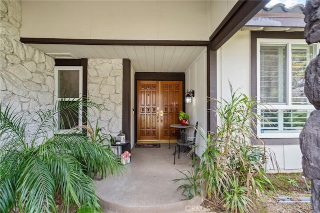 entrance to property featuring stone siding and covered porch