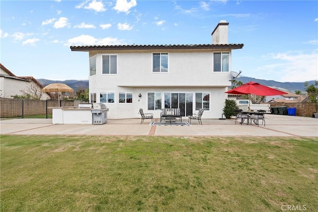 back of property featuring fence, a patio, a chimney, and a lawn