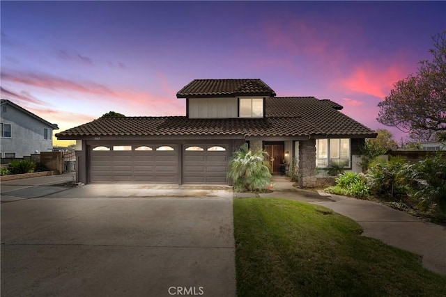 mediterranean / spanish-style house with a tile roof, an attached garage, and driveway