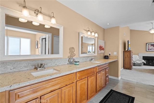 full bath with double vanity, visible vents, a fireplace, and a sink