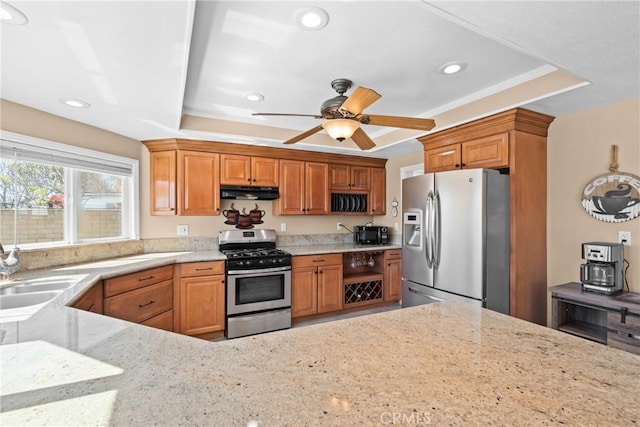 kitchen with light stone countertops, exhaust hood, a raised ceiling, appliances with stainless steel finishes, and recessed lighting