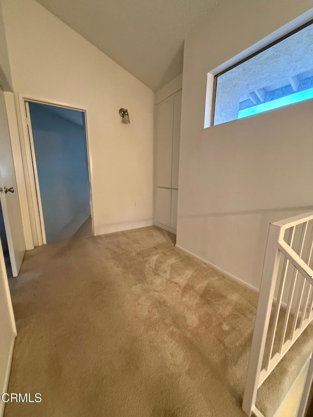 carpeted empty room featuring lofted ceiling