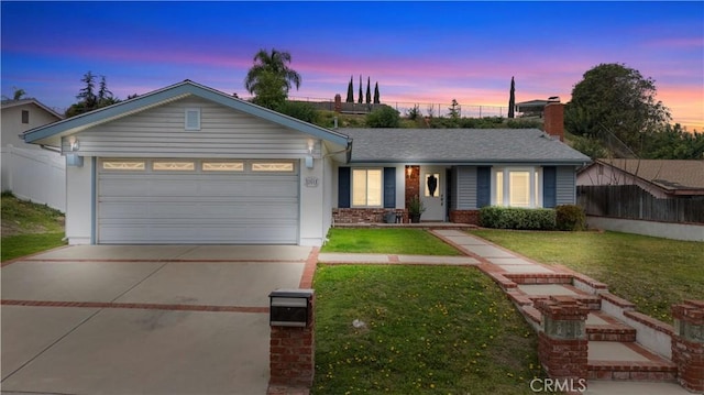 ranch-style house with a lawn, concrete driveway, roof with shingles, an attached garage, and fence