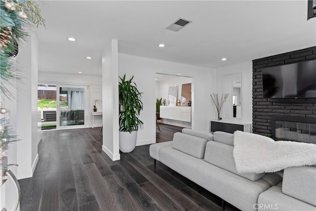 living room with baseboards, visible vents, dark wood-type flooring, a fireplace, and recessed lighting