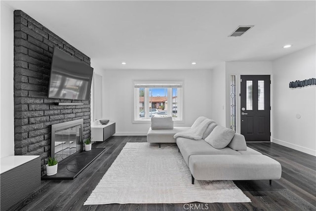 living area featuring visible vents, a fireplace, baseboards, and dark wood finished floors