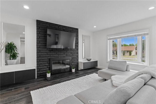 living room featuring baseboards, a brick fireplace, wood finished floors, and recessed lighting