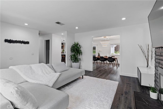 living area with dark wood-style floors, baseboards, visible vents, and recessed lighting