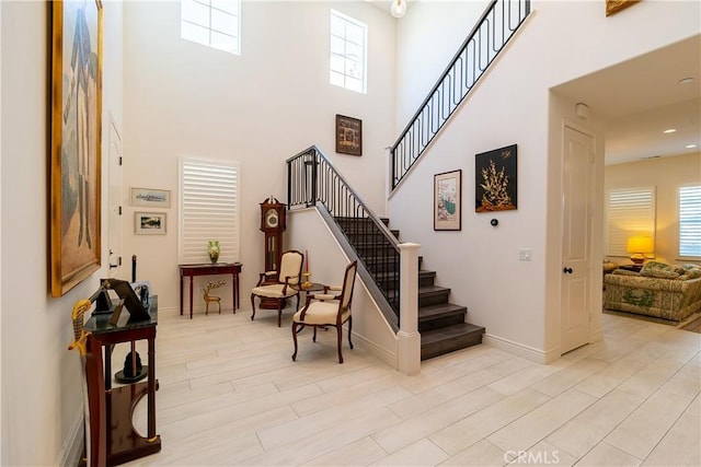 staircase featuring a high ceiling, wood finished floors, and baseboards