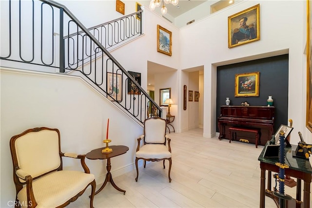 living area with a high ceiling, stairway, wood finished floors, and baseboards