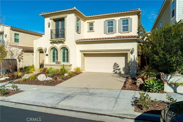 mediterranean / spanish home featuring a tile roof, stucco siding, concrete driveway, a balcony, and a garage