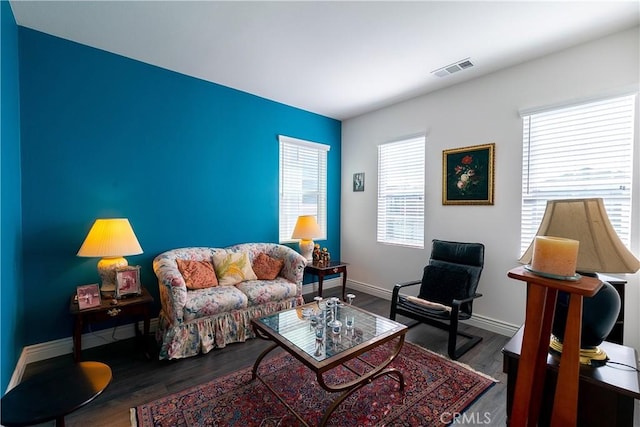 living area featuring visible vents, baseboards, and wood finished floors