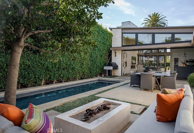 pool with a patio, outdoor dining space, an outdoor fire pit, and grilling area