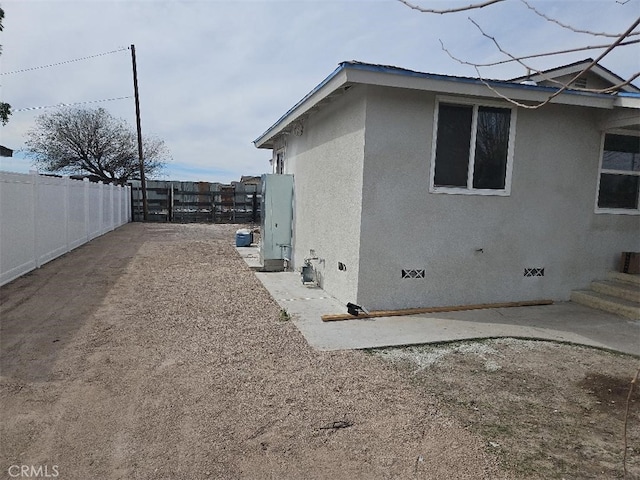 view of side of property featuring crawl space, a patio area, fence, and stucco siding