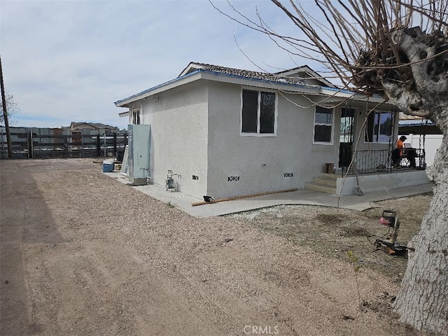 view of side of property featuring crawl space, fence, and stucco siding