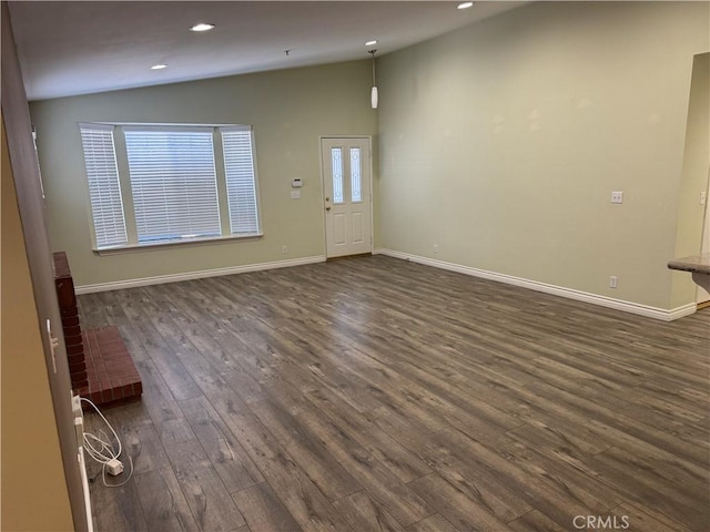 unfurnished living room featuring baseboards, vaulted ceiling, dark wood-style flooring, and recessed lighting