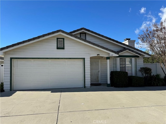 single story home with a garage, a chimney, fence, and concrete driveway