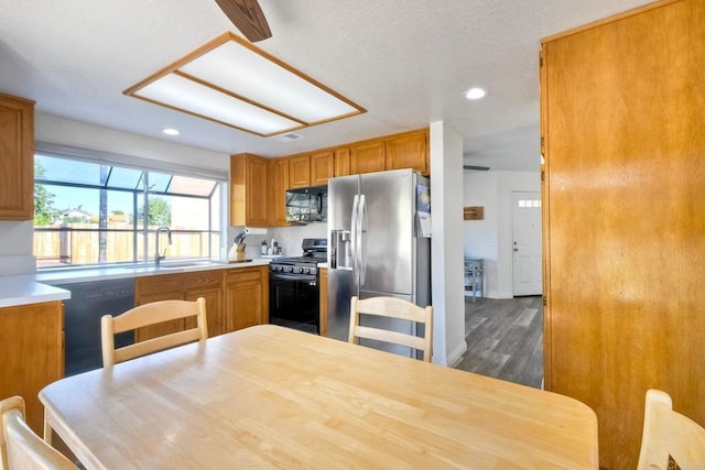 kitchen with recessed lighting, a sink, dark wood-style floors, black appliances, and brown cabinetry