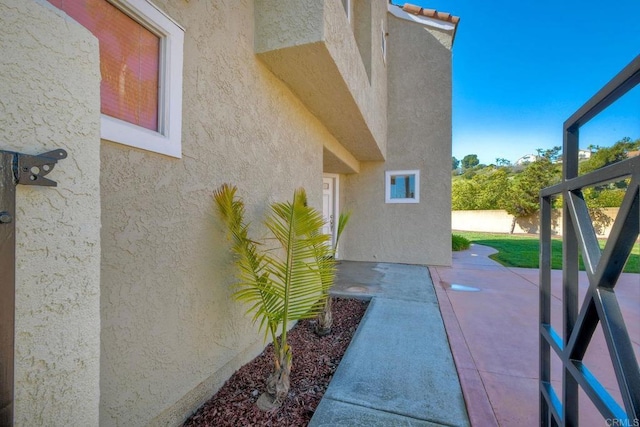 view of property exterior featuring a tile roof, fence, a patio, and stucco siding