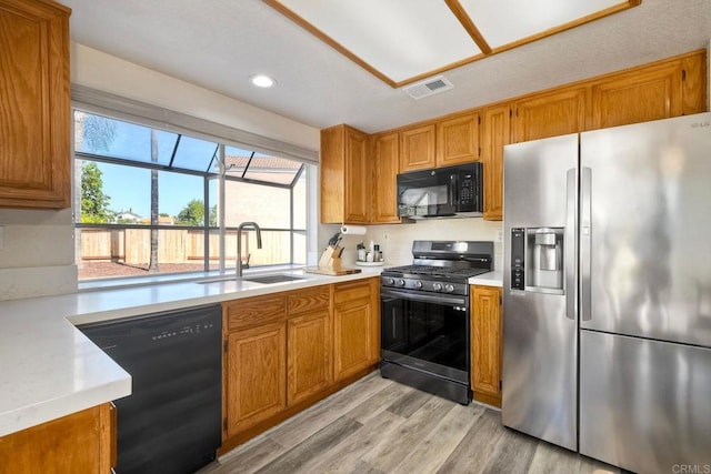 kitchen featuring black appliances, light countertops, a sink, and a wealth of natural light