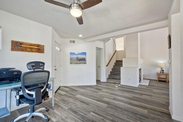 office space featuring ceiling fan, visible vents, baseboards, and wood finished floors