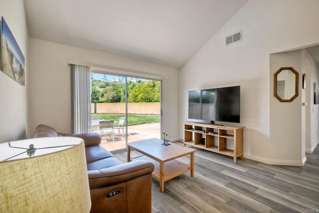 living room with lofted ceiling, wood finished floors, visible vents, and baseboards