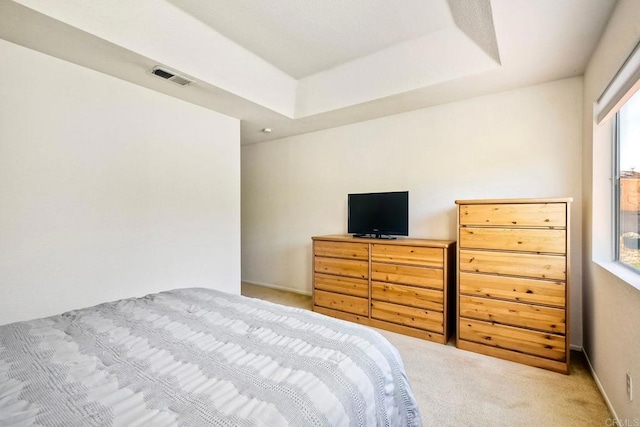 bedroom with carpet, visible vents, and a raised ceiling