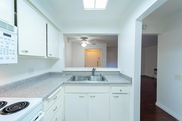 kitchen with white appliances, white cabinets, dark wood-style floors, light countertops, and a sink