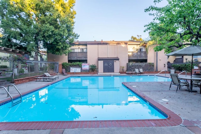 community pool with fence and a patio