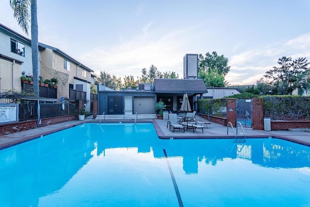 community pool with a patio and fence