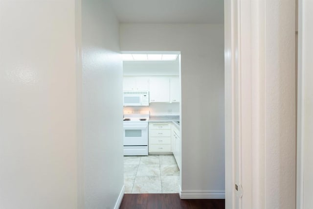 corridor featuring light wood finished floors and baseboards